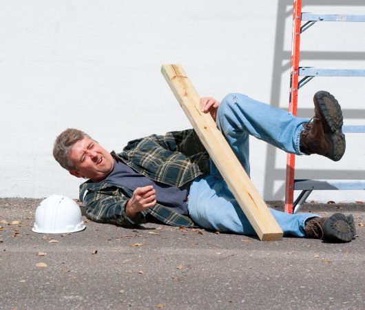 A man laying on the ground holding a wooden board.